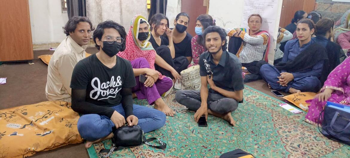 A group of individuals, some wearing masks, sitting on cushions in a room, part of a safe space for HIV/AIDS support in Lahore, Pakistan.