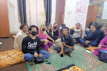 لاہور، پاکستان میں ایچ آئی وی / ایڈز کی مدد کے لئے محفوظ جگہ کے ایک حصے میں ایک کمرے میں کشنوں پر بیٹھے افراد کا ایک گروپ، کچھ ماسک پہنے ہوئے۔