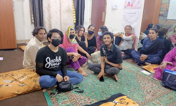 لاہور، پاکستان میں ایچ آئی وی / ایڈز کی مدد کے لئے محفوظ جگہ کے ایک حصے میں ایک کمرے میں کشنوں پر بیٹھے افراد کا ایک گروپ، کچھ ماسک پہنے ہوئے۔