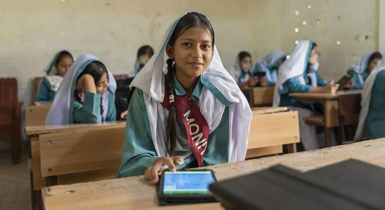 پاکستان میں ایک نوجوان لڑکی کلاس روم میں ٹیبلٹ استعمال کرتے ہوئے مسکرا رہی ہے۔ یہ سندھ لرننگ پاسپورٹ پروگرام کا حصہ ہے جو لڑکیوں کو ڈیجیٹل تعلیم کے ذریعے بااختیار بناتا ہے۔