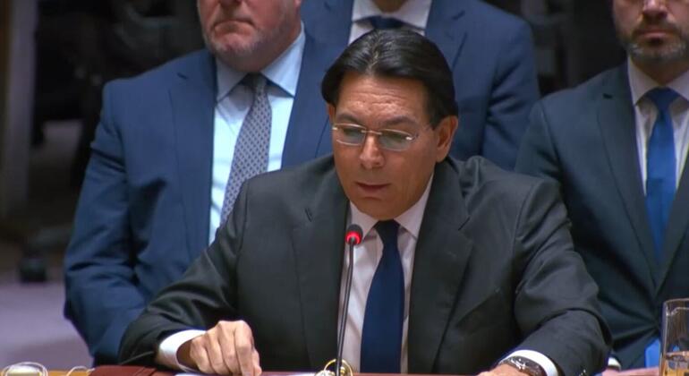 Мужчина в костюме выступает на заседании Организации Объединенных Наций с табличкой с надписью "ISRAEL" перед собой.