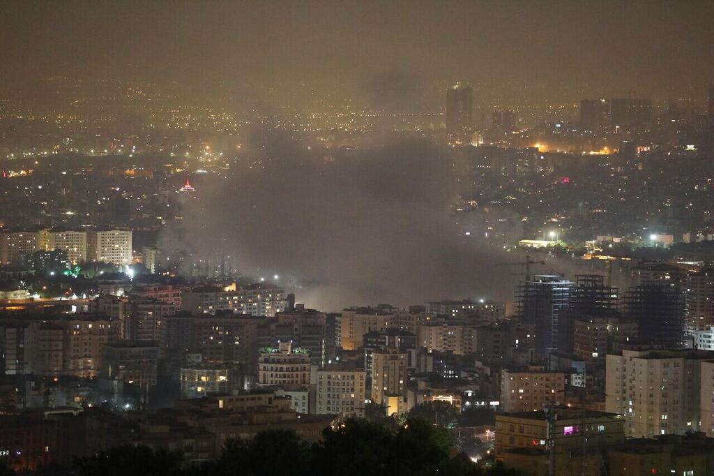 Un paisaje nocturno de la ciudad de Teherán, Irán, con humo que se eleva de un incendio en el área urbana.
