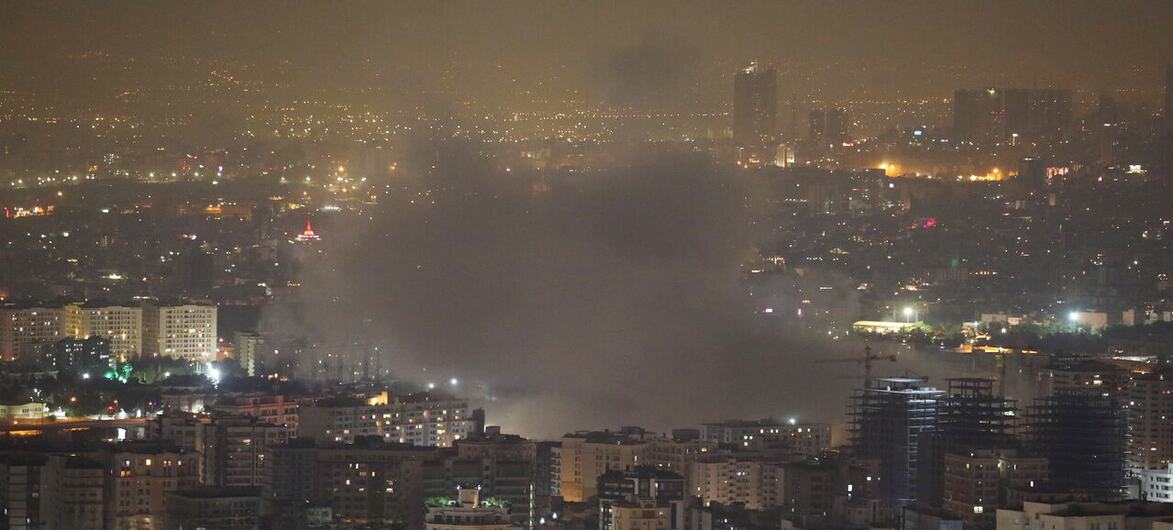 Uma paisagem noturna da cidade de Teerã, Irã, com fumaça subindo de um incêndio na área urbana.