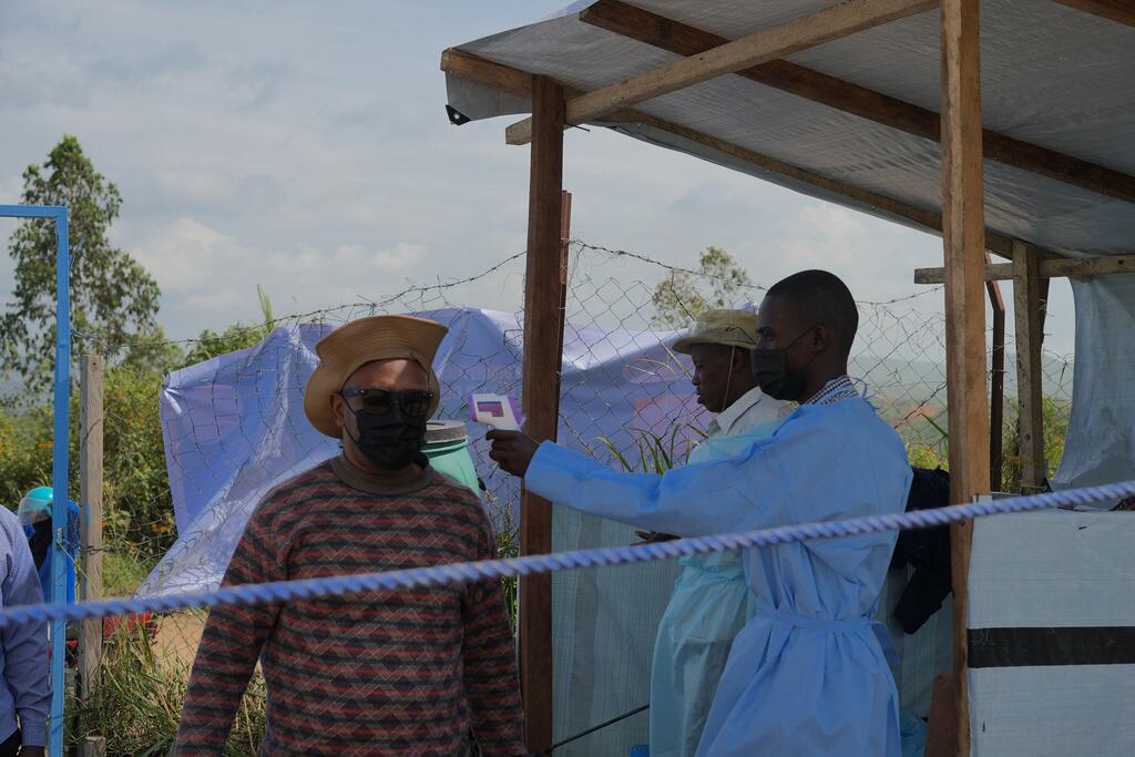 Un agent de santé examine un homme à l'entrée d'un établissement de santé dans la province d'Ituri, en République démocratique du Congo.
