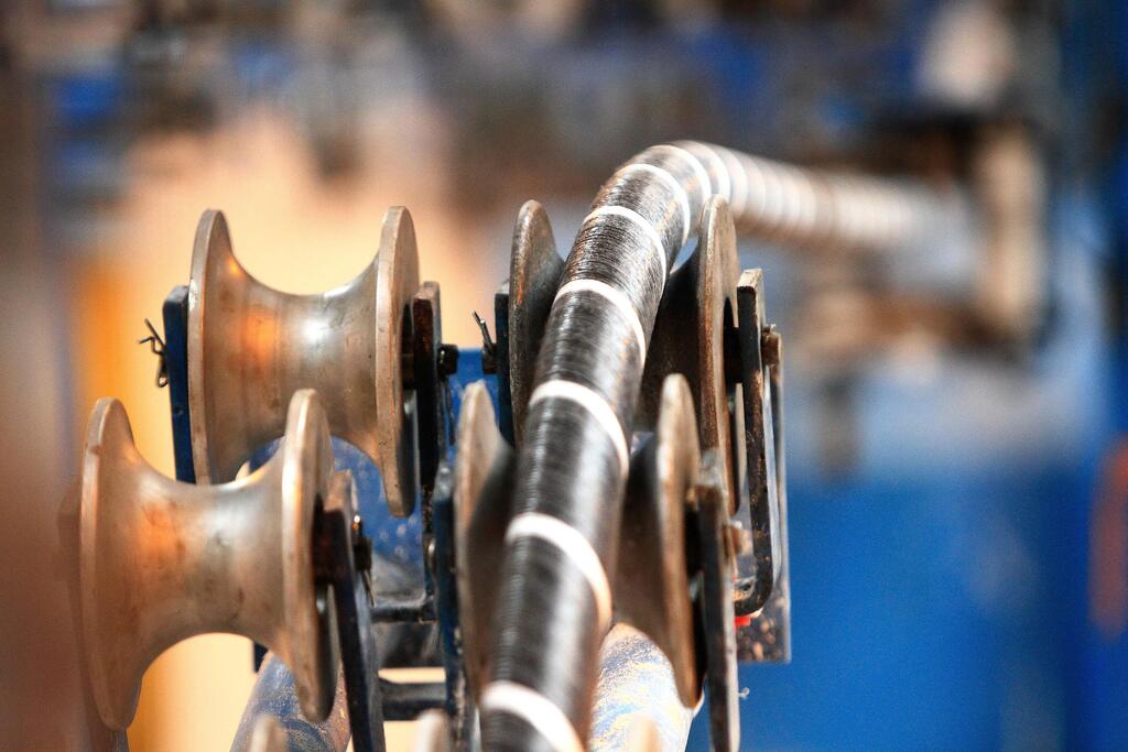 Una vista de cerca de un cable submarino envuelto en un gran carretillo industrial, resaltando los intrincados detalles del cable y la maquinaria utilizada en su despliegue.