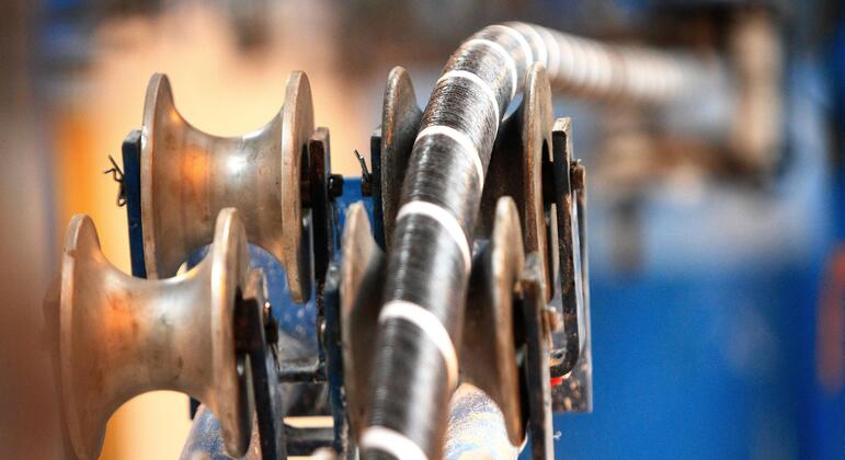 Ближайшее изображение подводного кабеля, закрученного на большую промышленную катушку, подчеркивает сложные детали кабеля и оборудования, используемых при его развертывании.