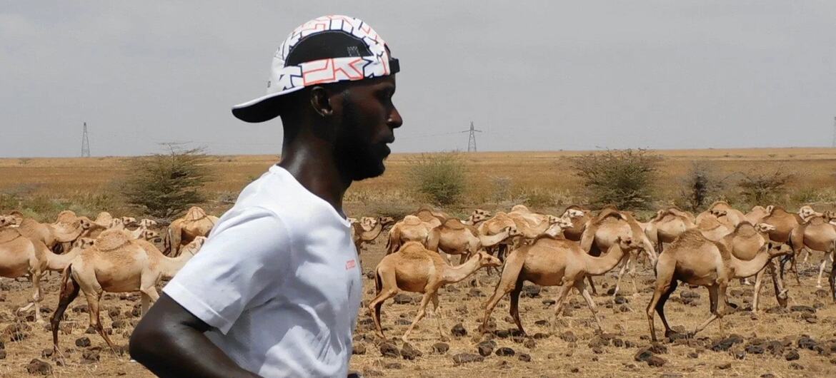 Deo Kato, a Ugandan-born activist, runs through a desert landscape with camels in the background during his 8,262-mile journey from Cape Town to London to challenge migration stereotypes.