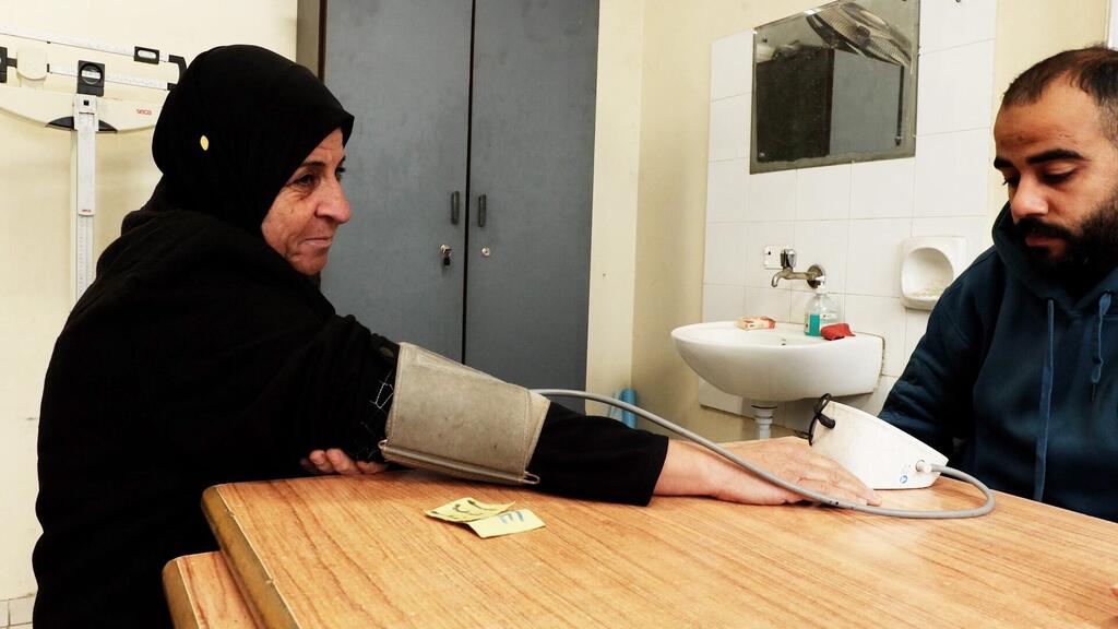امرأة فلسطينية لاجئة، أم جاسر، تتلقى علاجًا طبيًا في عيادة صحية للأونروا في نصيرات، غزة.