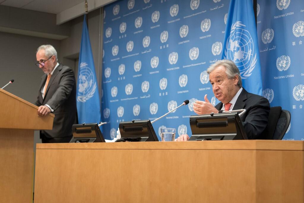 Katibu Mkuu António Guterres anazungumza katika mkutano wa waandishi wa habari, ameketi kwenye jukwaa na bendera za Umoja wa Mataifa na nembo nyuma.