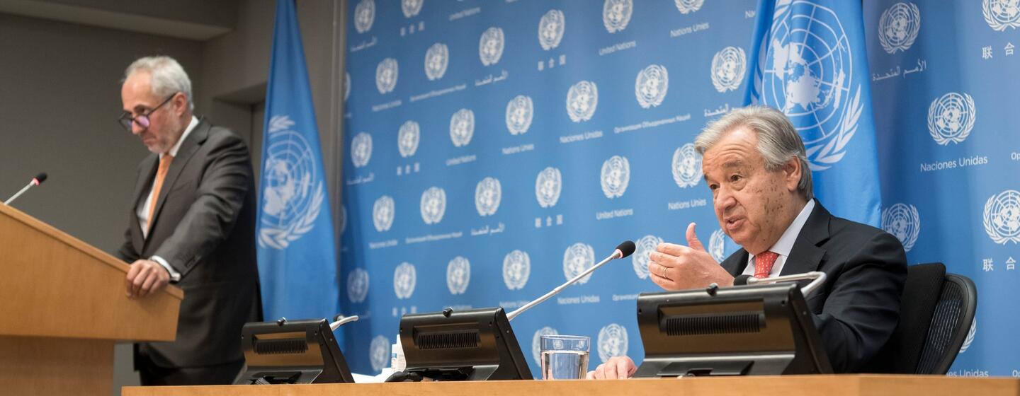 El secretario general António Guterres habla en una conferencia de prensa, sentado en un podio con banderas y logotipos de la ONU en el fondo.