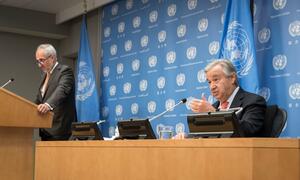 Secretary-General António Guterres (seated at right) speaks to reporters at a press conference at the UN Headquarters, in New York. Standing nearby is his spokesperson, Stéphane Dujarric.