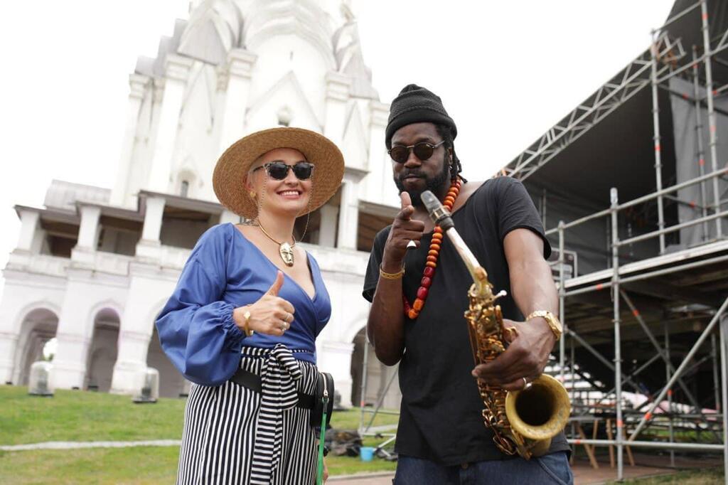 Maria Semushkina y Soweto Kinch (Reino Unido) posan juntos en Usadba Jazz en 2019, con Soweto Kinch sosteniendo un saxofón y Maria Semushkina haciendo un gesto de pulgar hacia arriba.