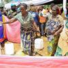 Mwanamke mmoja huko Beni, DRC, amemwaga maji kutoka kwenye kituo cha maji kilichopangwa hivi karibuni wakati wa mradi wa maji unaofadhiliwa na MONUSCO, huku wanajamii na wanajeshi wa kulinda amani wa Umoja wa Mataifa wakitazama.