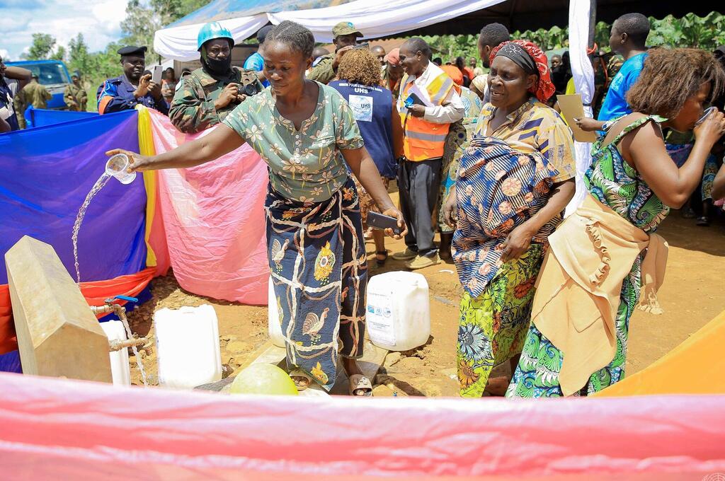 Mwanamke mmoja huko Beni, DRC, amemwaga maji kutoka kwenye kituo cha maji kilichopangwa hivi karibuni wakati wa mradi wa maji unaofadhiliwa na MONUSCO, huku wanajamii na wanajeshi wa kulinda amani wa Umoja wa Mataifa wakitazama.