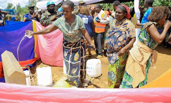 Mwanamke mmoja huko Beni, DRC, amemwaga maji kutoka kwenye kituo cha maji kilichopangwa hivi karibuni wakati wa mradi wa maji unaofadhiliwa na MONUSCO, huku wanajamii na wanajeshi wa kulinda amani wa Umoja wa Mataifa wakitazama.