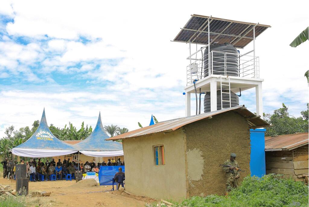 Projekti ya benki ya maji yenye nishati ya jua huko Beni, DRC, pamoja na wafanyakazi wa MONUSCO waliohudhuria tukio la jamii chini ya mahema ya bluu.