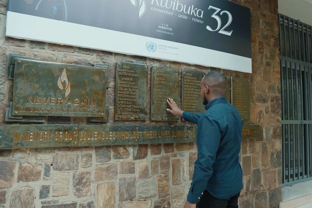 Mwanamume akigusa bamba la ukumbusho la kusherehekea wenzake wa Umoja wa Mataifa waliopoteza maisha wakati wa mauaji ya kimbari Rwanda 1994, chini ya bendera ya 'Kwibuka 32'.