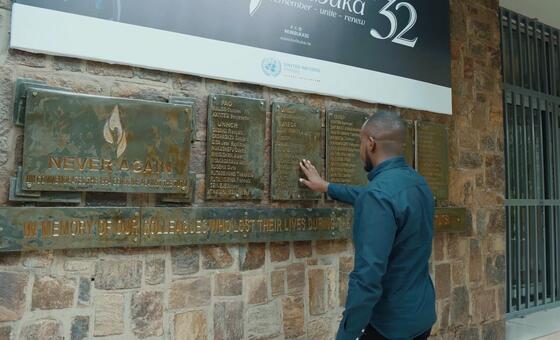 Mwanamume akigusa bamba la ukumbusho la kusherehekea wenzake wa Umoja wa Mataifa waliopoteza maisha wakati wa mauaji ya kimbari Rwanda 1994, chini ya bendera ya 'Kwibuka 32'.