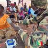 Un soldat sénégalais de la MINUSCA vérifie la tension artérielle d'une femme dans un village rural africain.