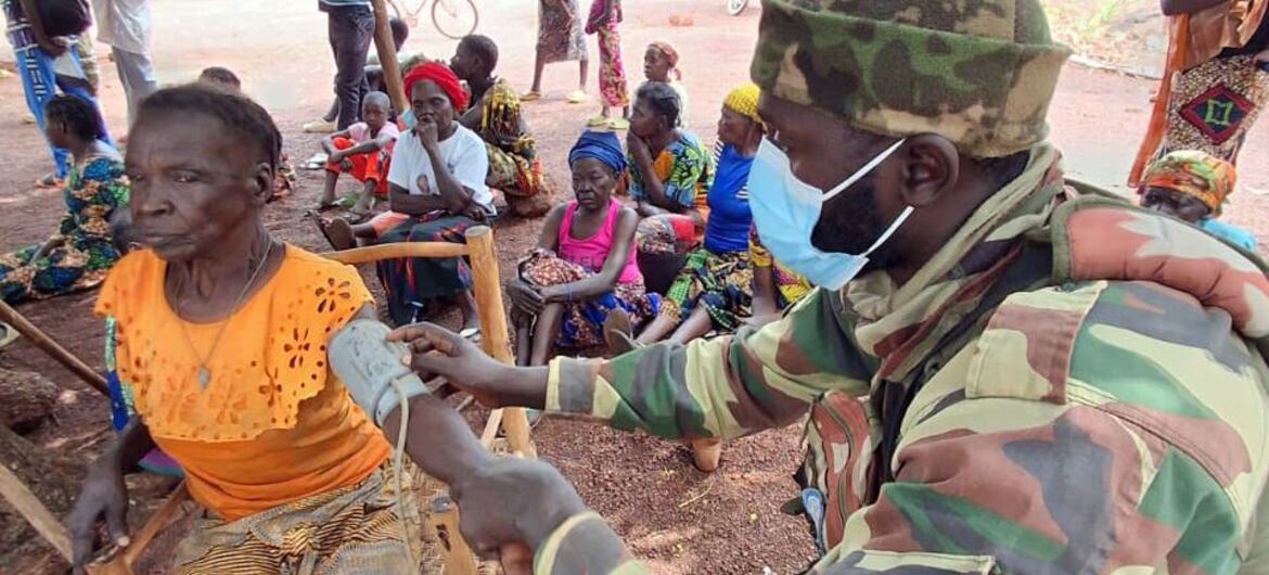 Un soldat sénégalais de la MINUSCA vérifie la tension artérielle d'une femme dans un village rural africain.