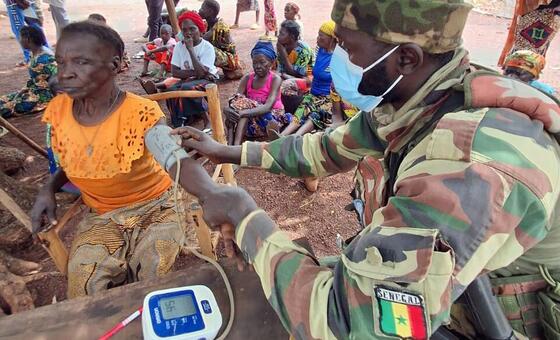 Un soldat sénégalais de la MINUSCA vérifie la tension artérielle d'une femme dans un village rural africain.