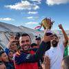 لاعب كرة القدم الفلسطيني أسعد العزابي يحمل كأس بطولة مخيمات نازحي رفح، يحتفل مع حشد من الشباب والأطفال في مواصي خان يونس.