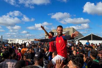 El futbolista desplazado Asaad Al-Azzabi, vestido con una camiseta de España, es cargado sobre los hombros de una multitud en un campamento de carpas en Al-Mawasi, Gaza.