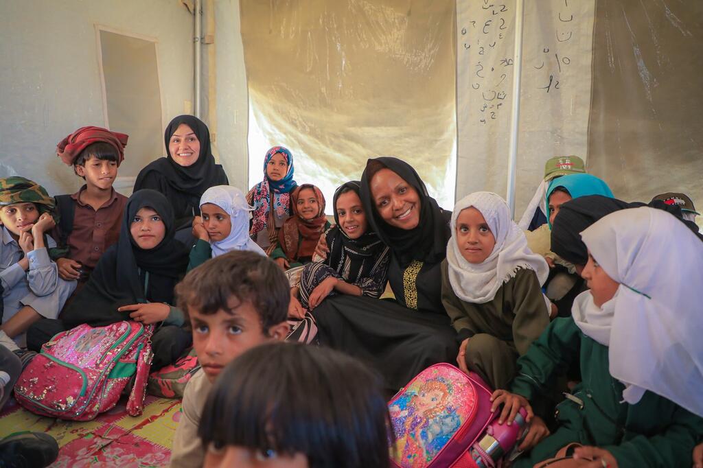 UNOCHA Deputy Secretary-General Joyce Msuya reads with children inside a tent at the Al Sumya displacement camp in Yemen.