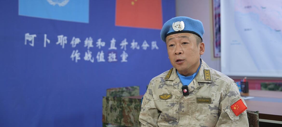 戴着蓝色贝雷帽、身穿迷彩服的中国联合国维和人员在指挥所进行简报时发表讲话。