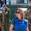 Kandice Ardiel, una portavoz femenina de la UNIFIL, con un chaleco azul de las Naciones Unidas y gafas de sol, de pie frente a varios hombres de la fuerza de paz con uniformes militares.