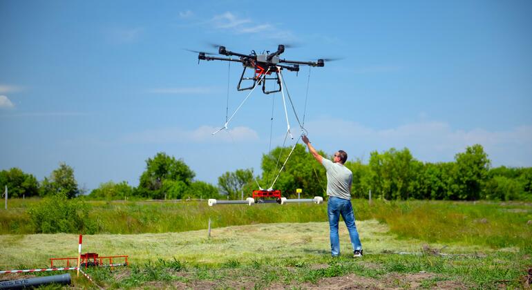 Мужчина управляет дроном, оснащенным технологией обнаружения мин, на поле в Украине в рамках гуманитарных усилий ПРООН.
