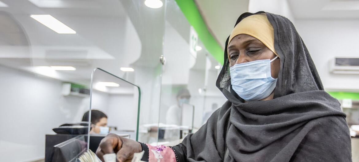 امرأة لاجئة سودانية ترتدي قناعًا وحجابًا تحسب النقود على عداد أثناء برنامج للمساعدات النقدية التابع للمفوضية السامية للأمم المتحدة لشؤون اللاجئين في مصر.