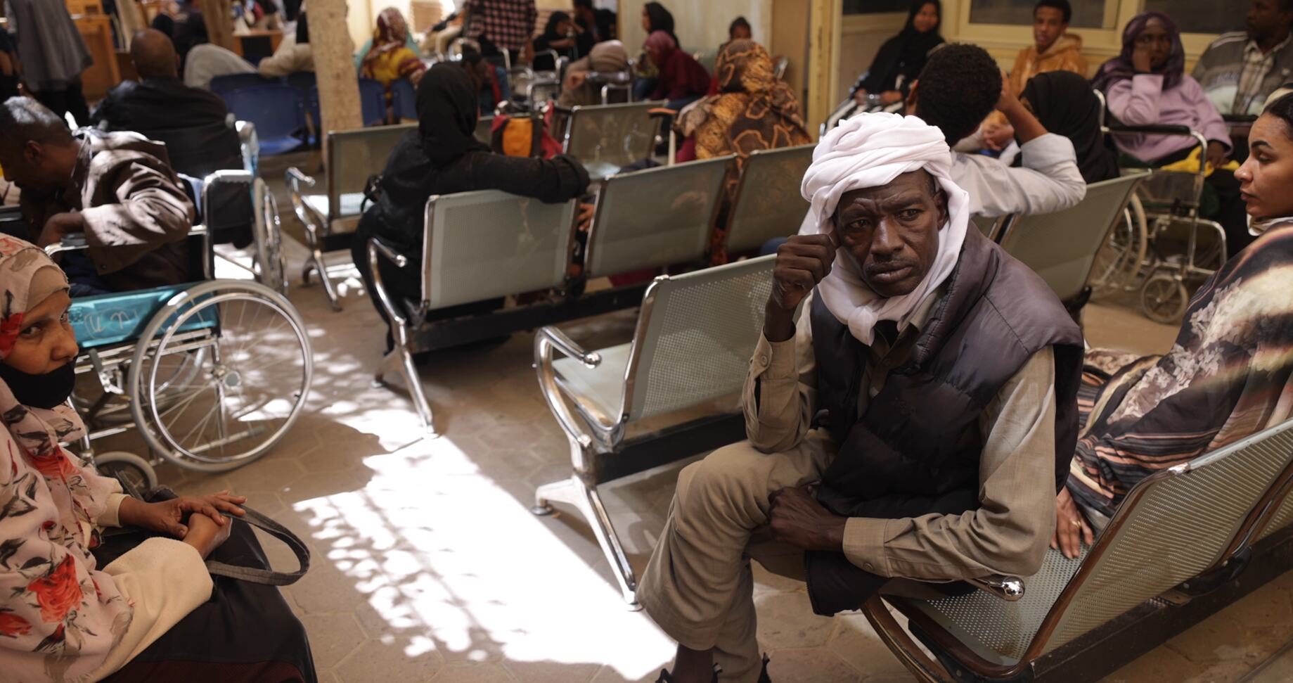 ایک سوڈانی پناہ گزین مصر میں یونائیٹڈ نیشنز ہائی کمشنر برائے مہاجرین (UNHCR) کے رجسٹریشن سینٹر میں ایک مصروف انتظار گاہ میں بیٹھا ہے۔
