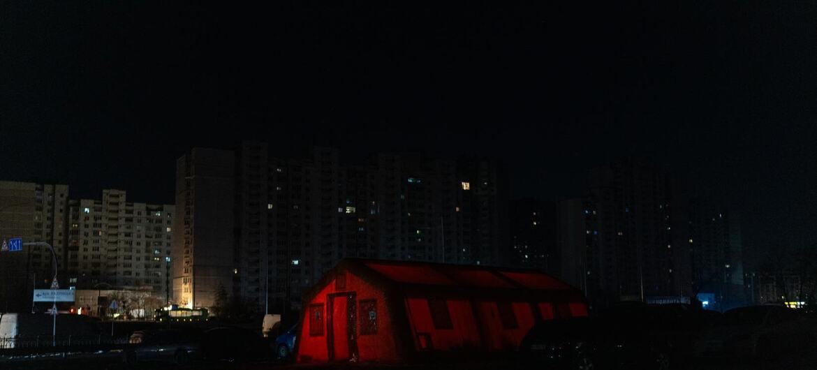 Красная палатка, освещенная ночью в заснеженном украинском городе.