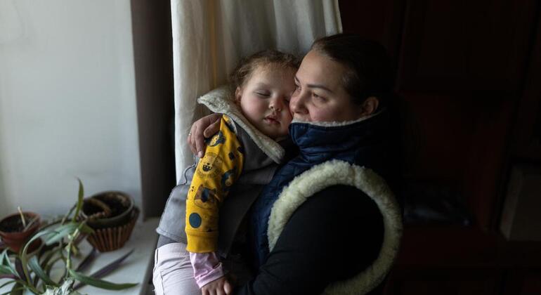 Une mère accroche son enfant endormi dans un cadre chaleureux en hiver.