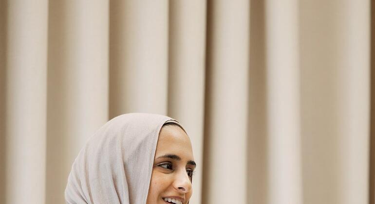 ماريام سوليكا، زعيمة الشباب في أهداف التنمية المستدامة التابعة للأمم المتحدة، تتحدث في مؤتمر بينما تجلس على المنصة مع لوحة.