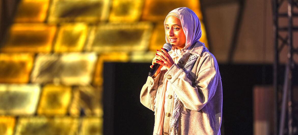 ماريام سوليكا، زعيمة الشباب في أهداف التنمية المستدامة التابعة للأمم المتحدة، تتحدث على المسرح بينما تحمل الميكروفون.