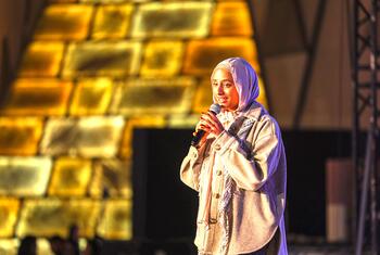 ماريام سوليكا، زعيمة الشباب في أهداف التنمية المستدامة التابعة للأمم المتحدة، تتحدث على المسرح بينما تحمل الميكروفون.