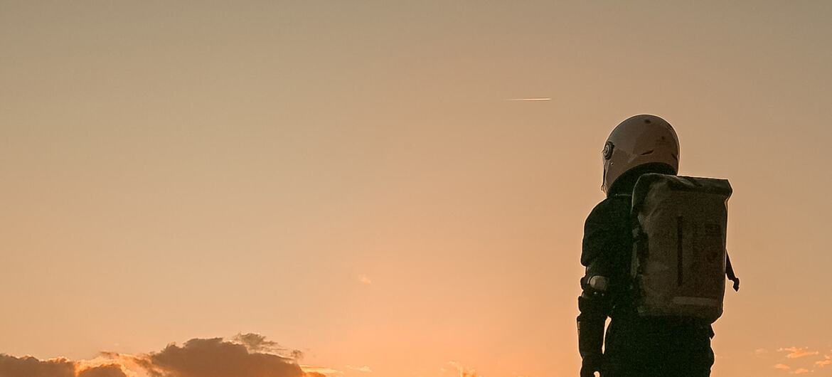 Sahbaa Shawa، زعيم الشباب في أهداف التنمية المستدامة 2025، يقف في مشهد صحاري عند غروب الشمس يرتدي بدلة رائد فضاء خلال أول مهمة مشابهة للأردن.