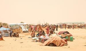 Sudanese refugees displaced by conflict gather in Tiné, Chad, waiting for relocation to a temporary site amid scarce resources and harsh conditions.
