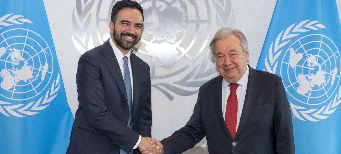 El secretario general de la ONU, António Guterres, estrecha la mano con Zohran Mamdani, alcalde de la ciudad de Nueva York, frente a las banderas de la ONU.