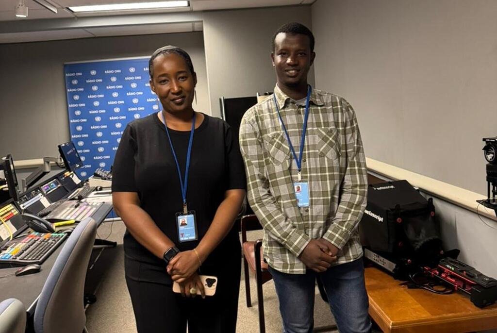 Mwanamke wa Kenya na mwanamume wa Kenya wamesimama pamoja katika studio ya utangazaji. Wanavaa beji za kitambulisho na kamba. Nyuma, kuna mandhari ya bluu na nembo ya 'K400 OMU', na vifaa mbalimbali vya sauti na utangazaji vinaonekana kwenye dawati.