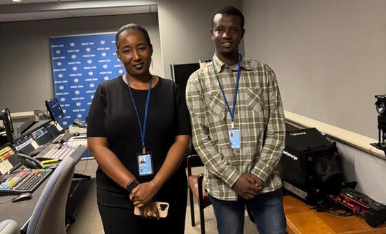 Mwanamke wa Kenya na mwanamume wa Kenya wamesimama pamoja katika studio ya utangazaji. Wanavaa beji za kitambulisho na kamba. Nyuma, kuna mandhari ya bluu na nembo ya 'K400 OMU', na vifaa mbalimbali vya sauti na utangazaji vinaonekana kwenye dawati.