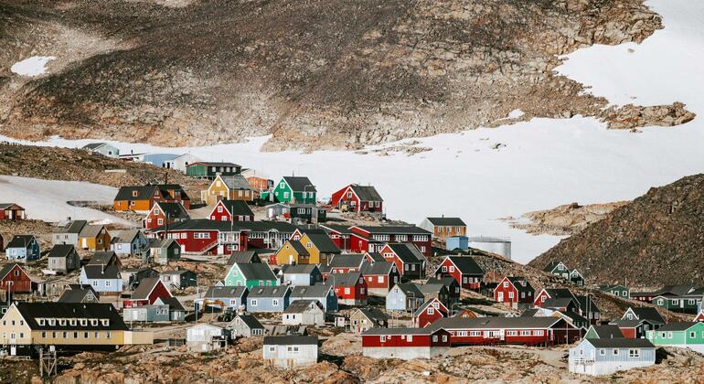 Un vibrante grupo de casas coloridas en Nuuk, Groenlandia, anidadas entre montañas nevadas y terreno rocoso.