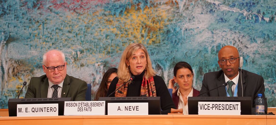 Um painel de oradores em uma reunião do Conselho de Direitos Humanos. Uma mulher com cabelo loiro está falando em um microfone. À sua esquerda está um homem com óculos e à sua direita está um homem negro com óculos. Placas de nomes identificam 'M. E. QUINTERO', 'A. NEVE', e 'VICE-PRESIDENTE'.