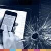 Mãos segurando um smartphone e um tablet ao lado de uma tela rachada com sobreposição de código binário, simbolizando cibercrime e ameaças à segurança digital.