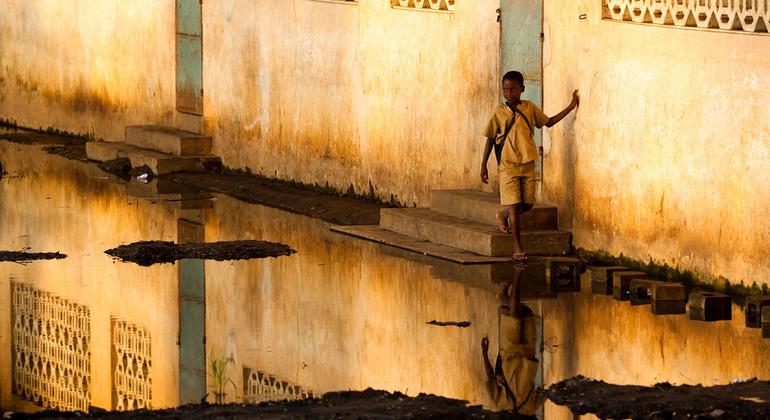 Um menino pisa em blocos de concreto para evitar enchentes ao deixar a escola em Mono, Benin