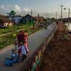 عائلة تمشي على طول جدار احتياطي تم بناؤه لمنع فيضانات المد في مقاطعة جاوة الوسطى، إندونيسيا.