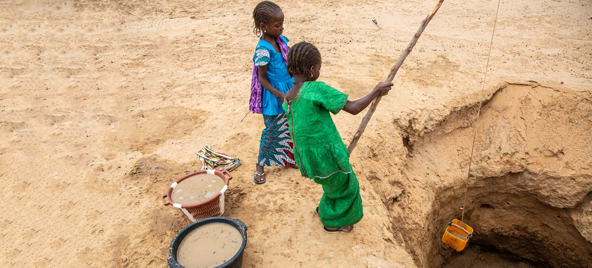 Jovens buscam água em poço cavado no solo na Mauritânia