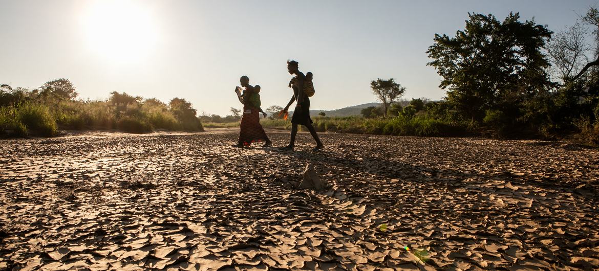 Mulher caminha para casa através do leito seco de um rio na Zâmbia.